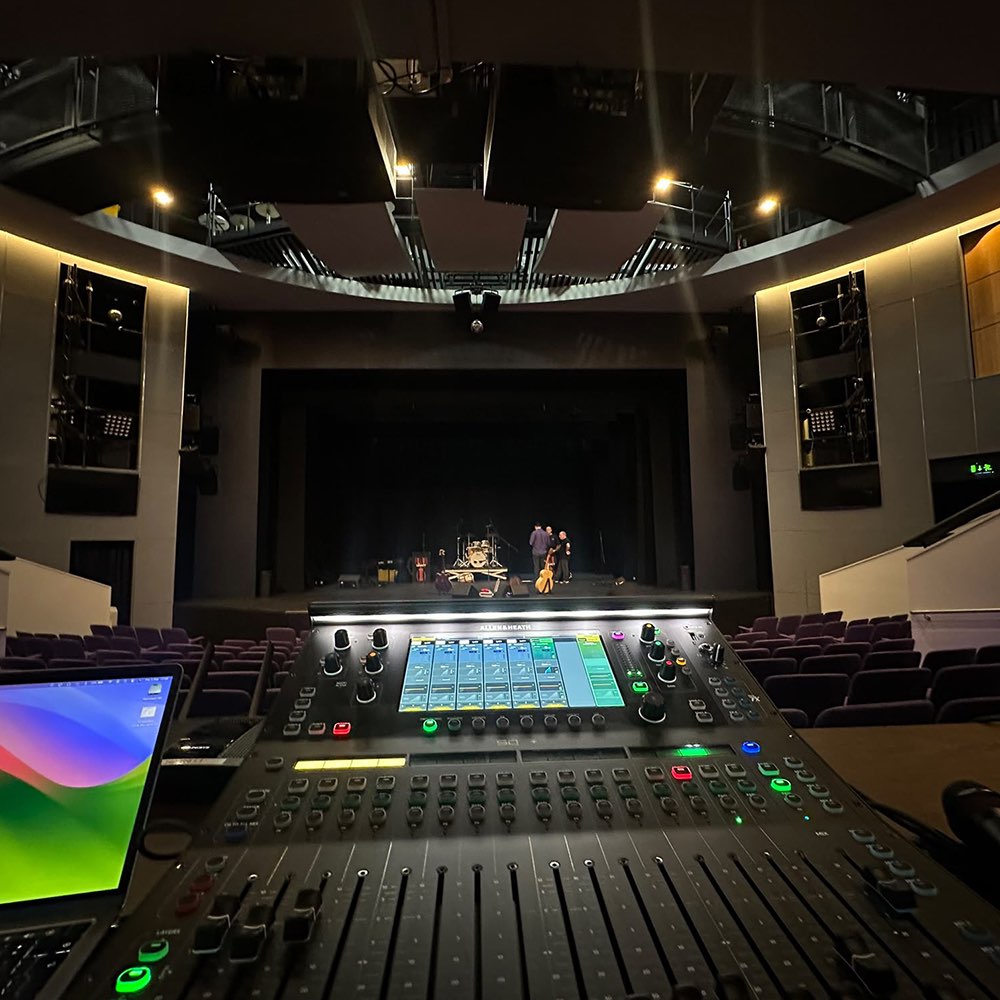 View from the sound mixing desk across an empty theatre as people prepare the stage before a live show